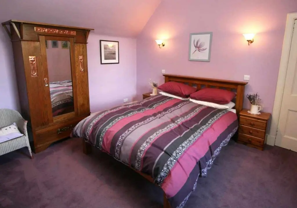 a bedroom with a large bed with red pillows at Cluny Mains in Newtonmore