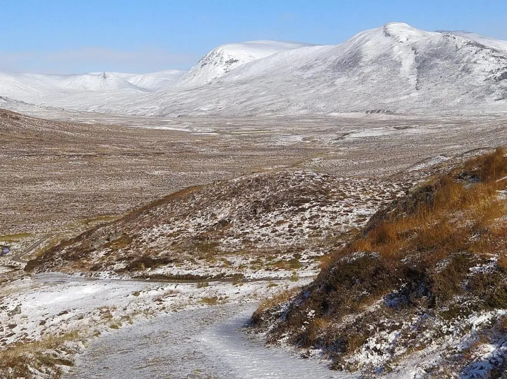 a snow covered mountain with a road in the foreground at Cluny Mains in Newtonmore
