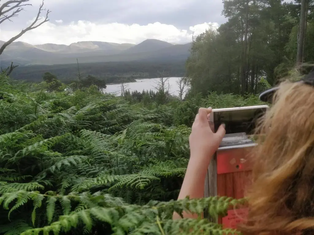 a woman taking a picture of a forest with a camera at Cluny Mains in Newtonmore