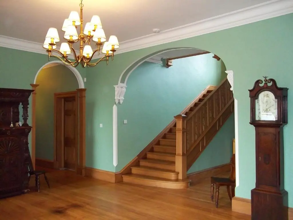 a staircase in a room with a chandelier and a clock at Carnach House in Nairn