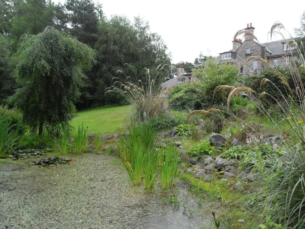 a garden with a house in the background at Carnach House in Nairn