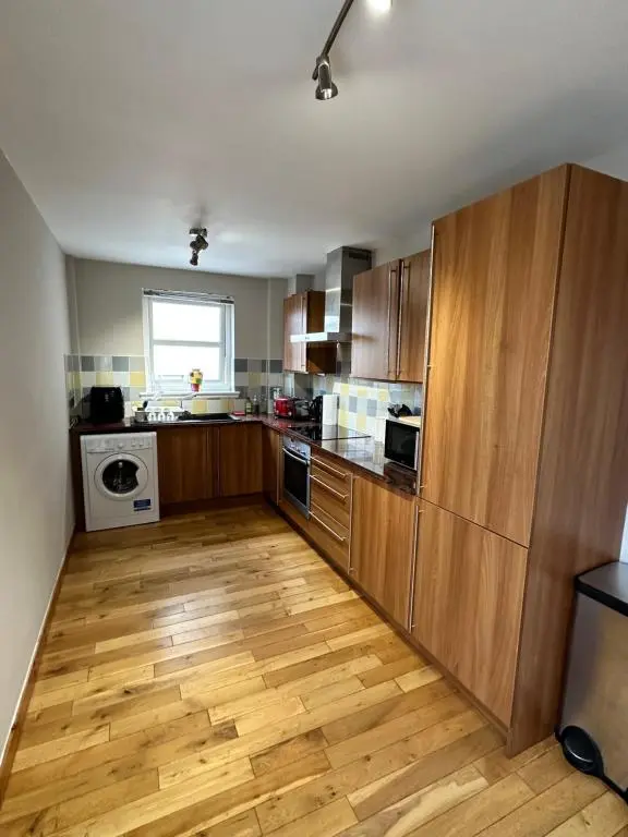 a kitchen with wooden cabinets and a wooden floor at Metro 8 Inverness City Centre in Inverness