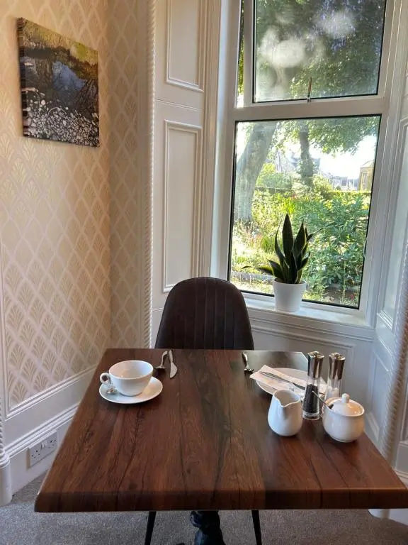 a wooden table with two chairs and a window at Glen Lyon Lodge Bed and Breakfast in Nairn