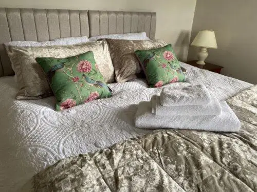 a bed with green and white sheets and pillows at Glen Lyon Lodge Bed and Breakfast in Nairn