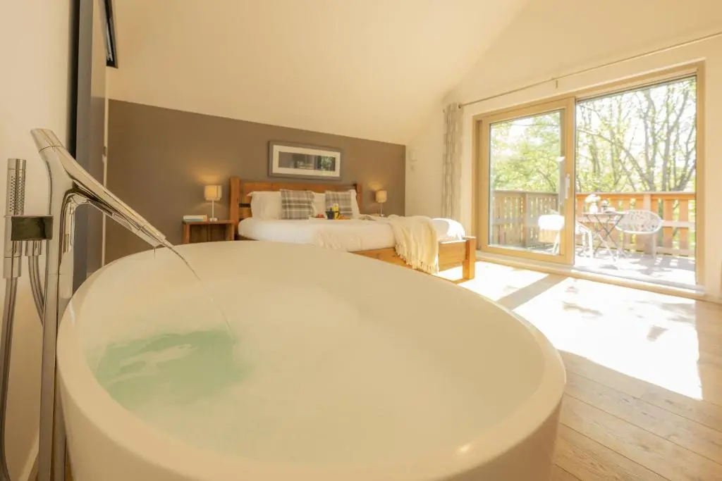 a bathroom with a tub and a bedroom at The Neuk in Kincraig