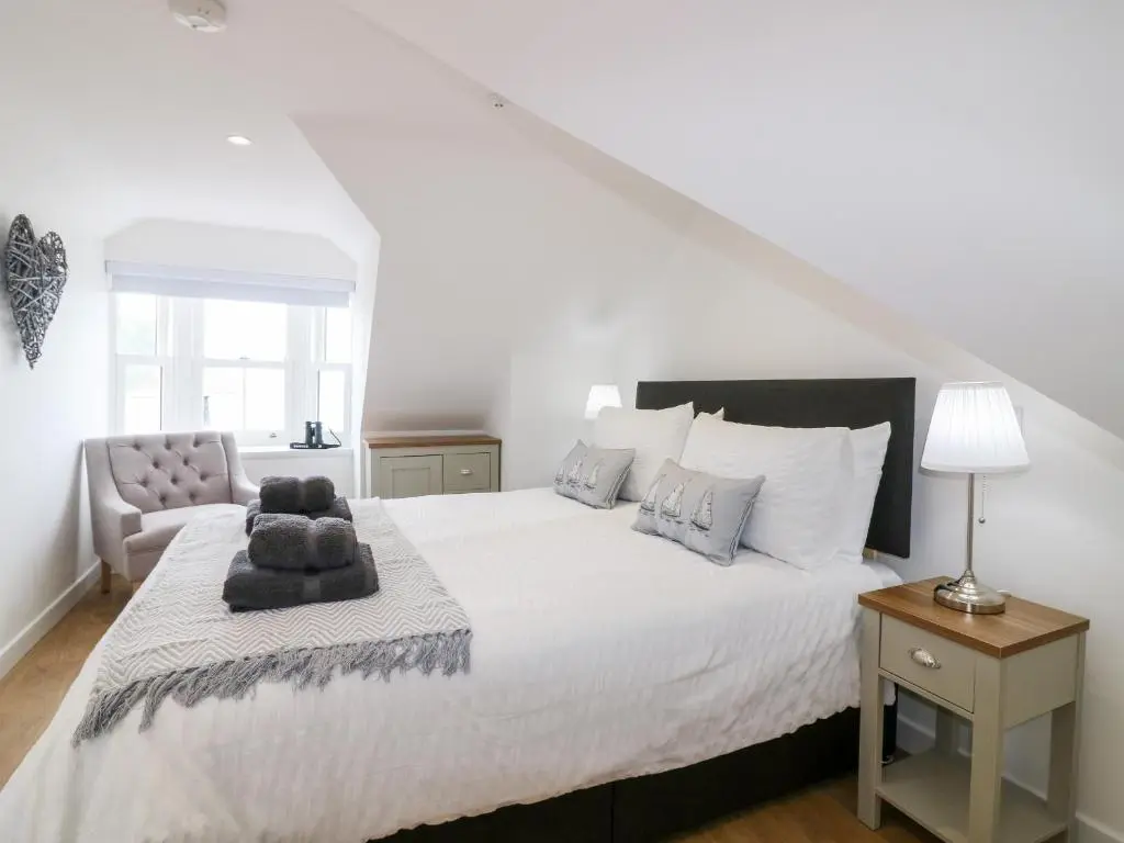 a white bedroom with a large bed and a chair at 111A Main Street in Banff