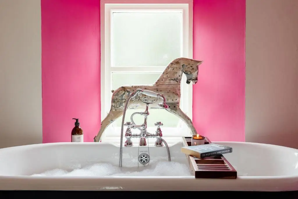 a bath tub in a bathroom with pink walls at Exclusive use - The Coach House in Banchory