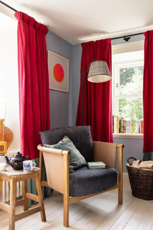 a living room with red curtains and a chair at Exclusive use - The Coach House in Banchory