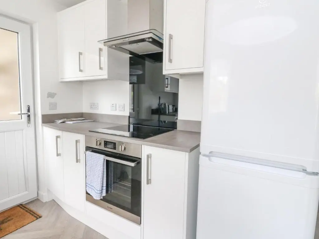 a kitchen with white cabinets and a stove top oven at Anchor Cottage in Elgin