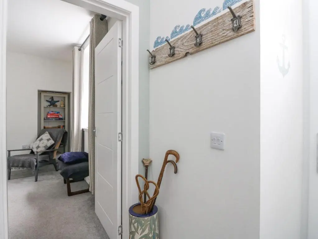 a hallway with an open door with a shelf on the wall at Anchor Cottage in Elgin