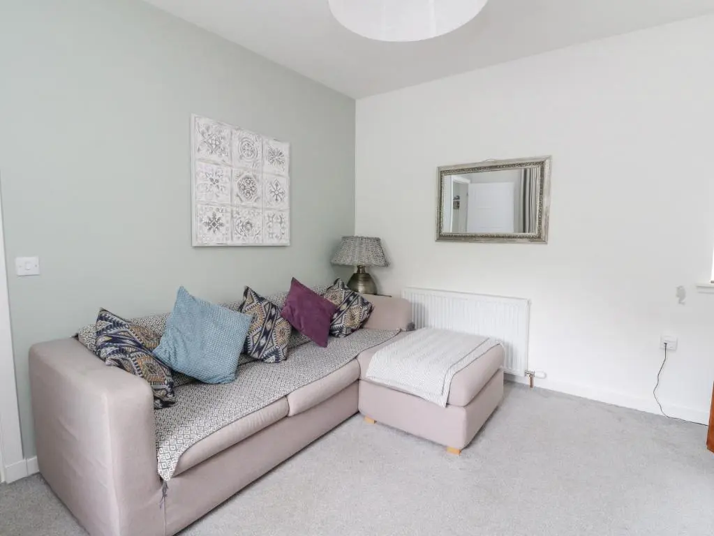 a living room with a couch and a mirror at Anchor Cottage in Elgin