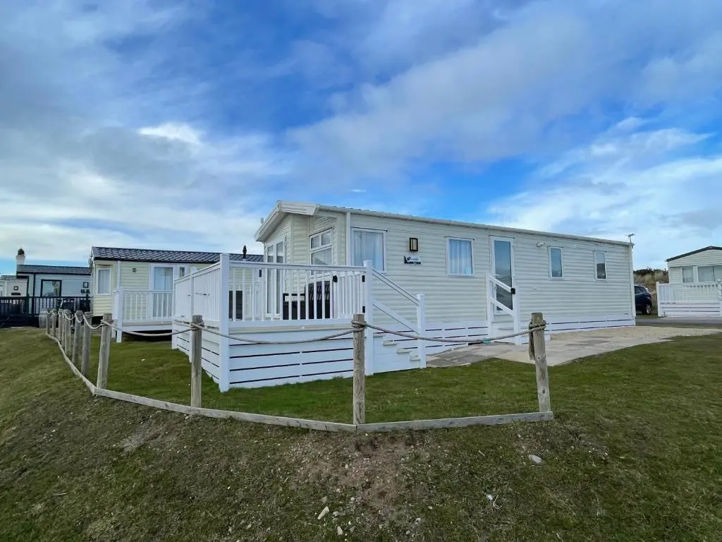 a white house with a fence in front of it at Fairview Caravan Hire in Lossiemouth