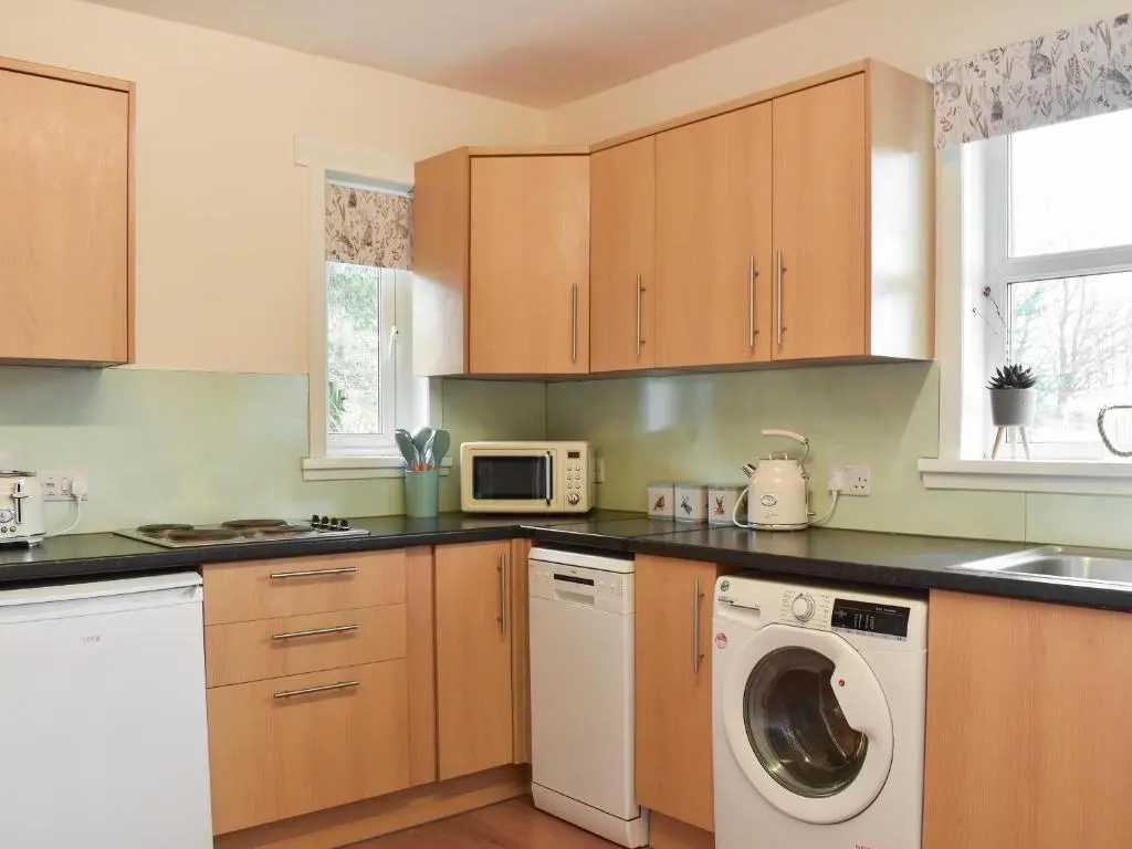 a kitchen with a washing machine and a microwave at Muir Cottage - Uk44788 in Bridge of Alford