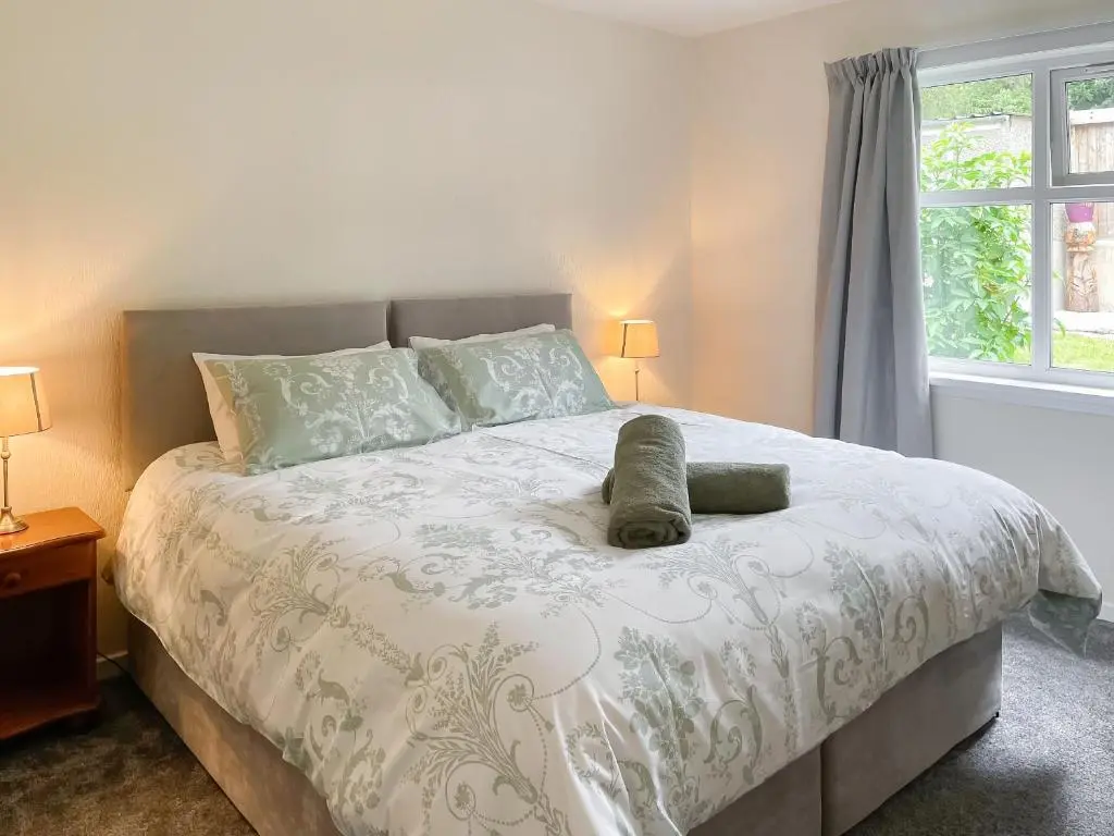 a bedroom with a bed with a white comforter and a window at Muir Cottage - Uk44788 in Bridge of Alford