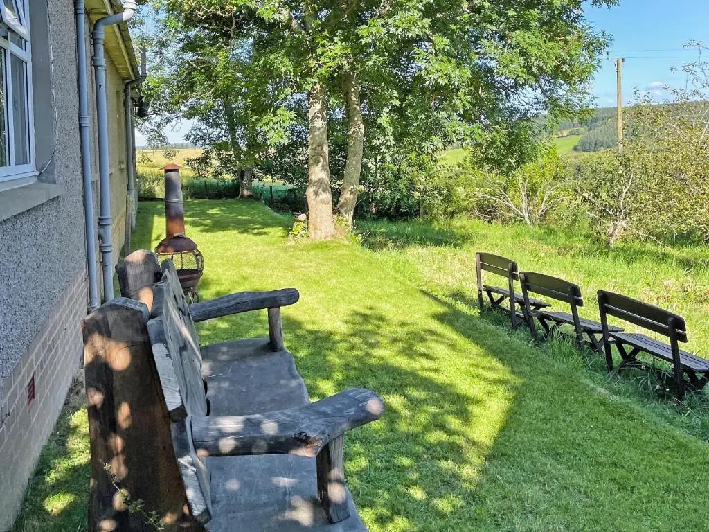 two benches sitting on the side of a house at Damil Cottage - Uk44789 in Bridge of Alford