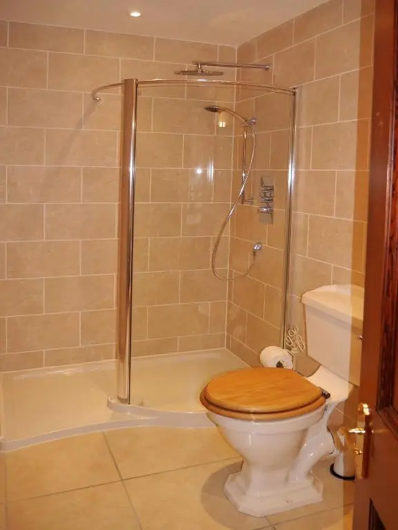 a bathroom with a shower and a toilet with a wooden seat at Tali Ayer in Nairn