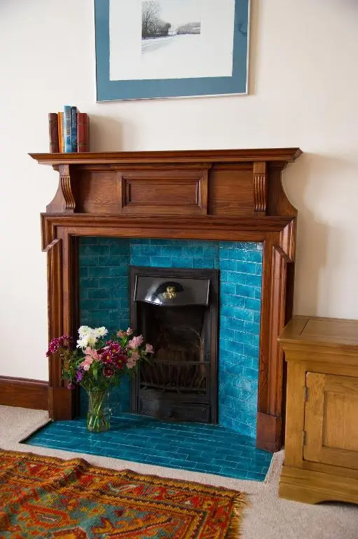 a blue brick fireplace with a vase of flowers at Tali Ayer in Nairn