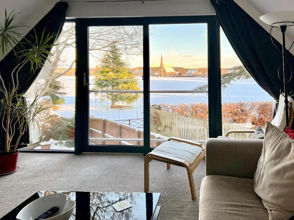 a living room with a view of the water at Cedar Cottage in Aboyne