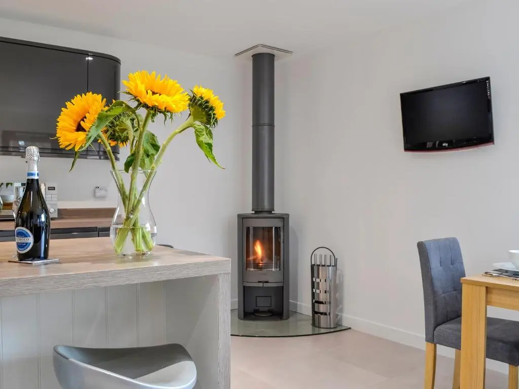 a living room with a fireplace and a vase of flowers at Cedar Cottage in Aboyne