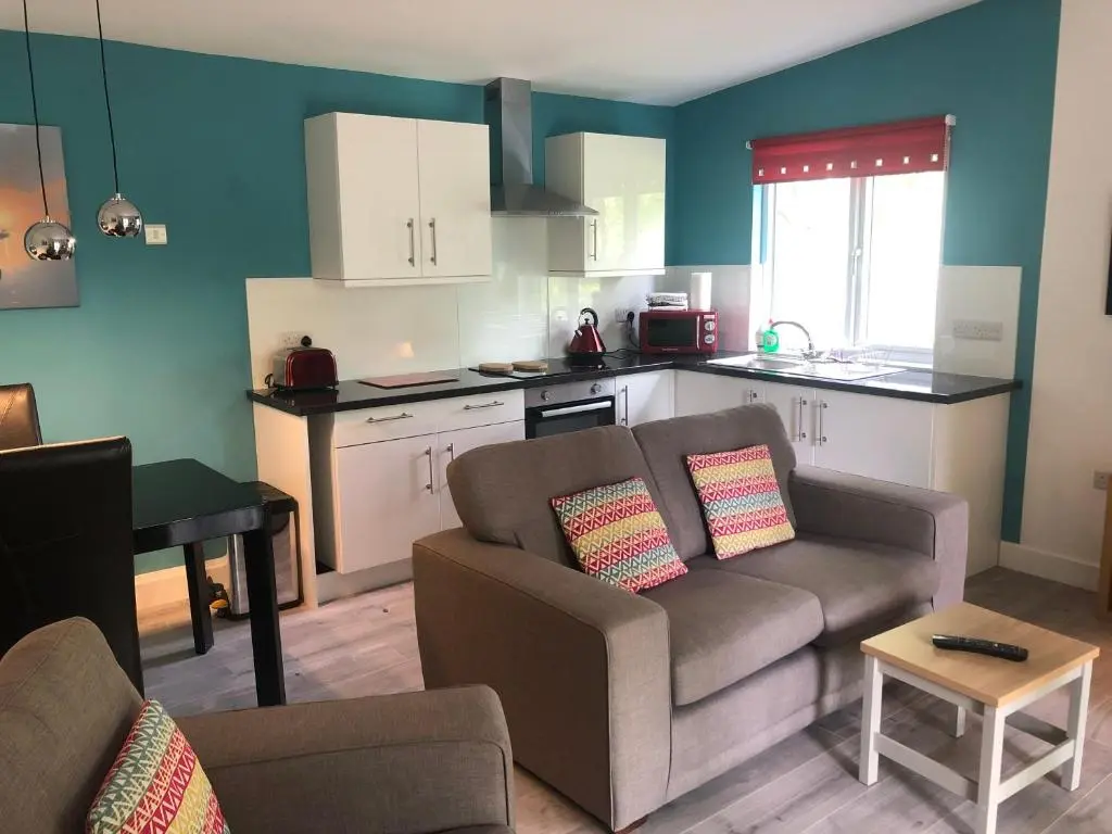 a living room with a couch and a kitchen at The South Cabin at Easter Arr in Nairn