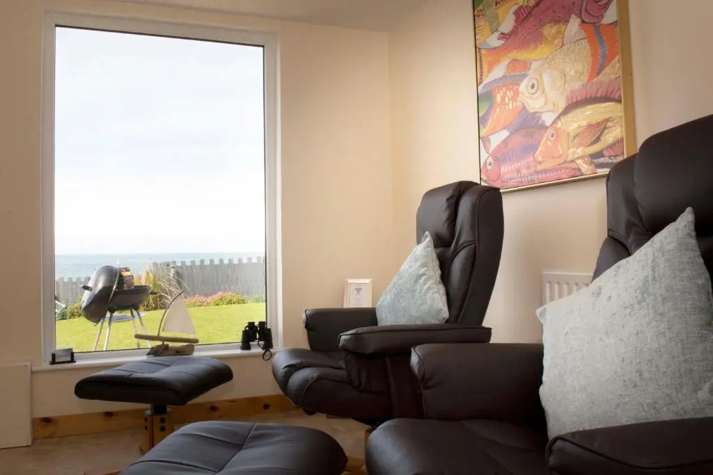 a living room with two chairs and a window at Seafront holiday home in Findochty in Findochty