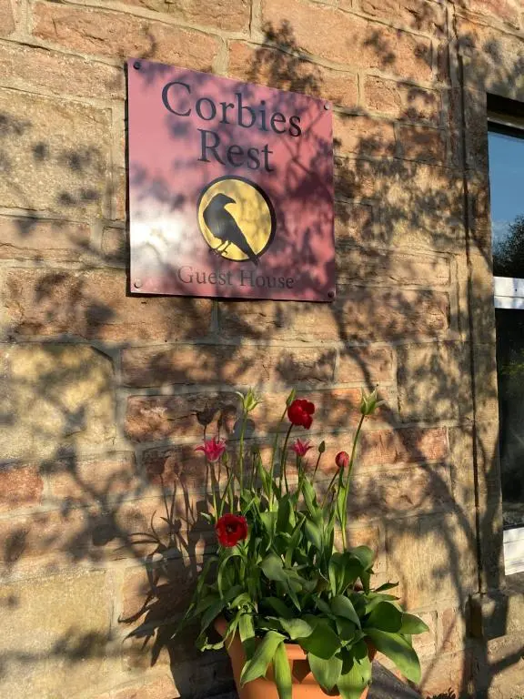 a sign on a brick wall with a potted plant at Room Only Corbies Rest in Inverness