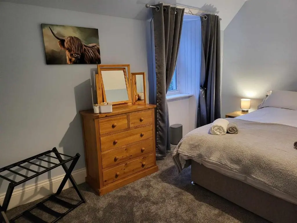 a bedroom with a bed and a dresser with a mirror at 16 Northcote Street, Wick in Wick
