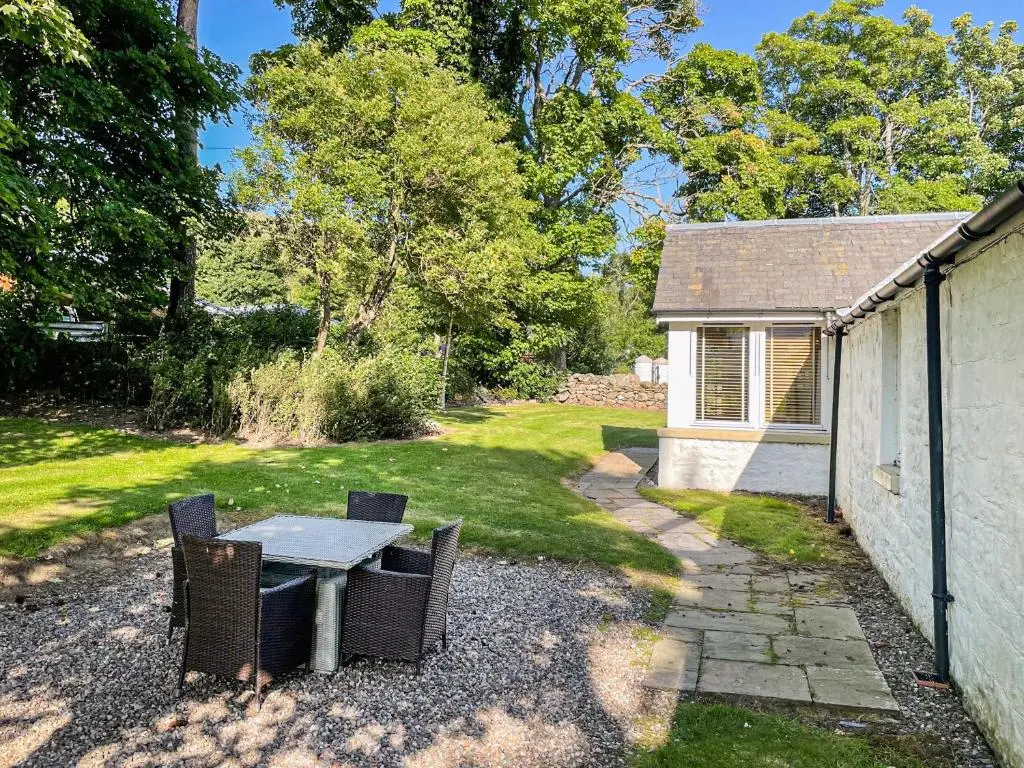 a patio with a table and chairs in a yard at Brandy Cottage - Ukc6855 in Millton of Clova
