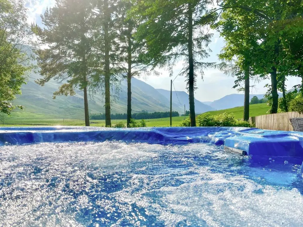 a swimming pool with blue water and trees and mountains at The Old Manse - Ukc6854 in Millton of Clova