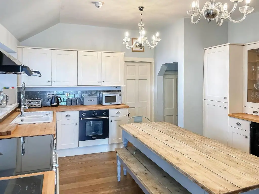 a kitchen with white cabinets and a wooden table at The Old Manse - Ukc6854 in Millton of Clova