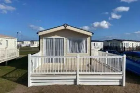 a small house with a white fence in a yard at Silver sands holiday park in Lossiemouth