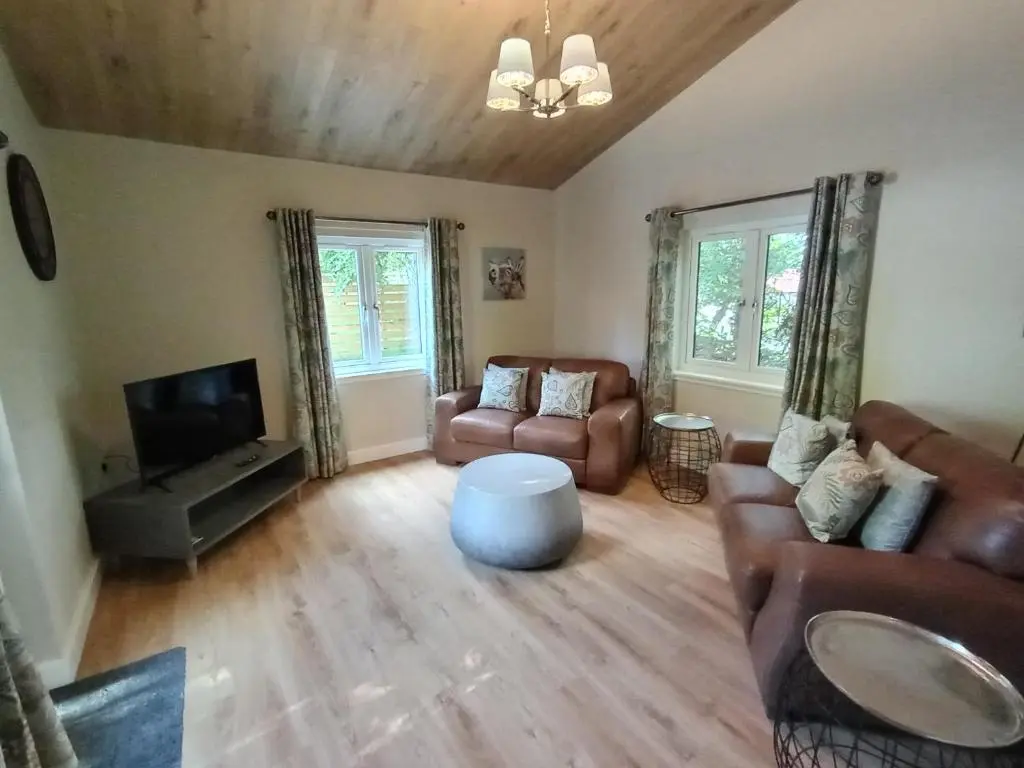 a living room with a couch and a tv at Breckland Lodge 1 with Hot Tub in Belladrum