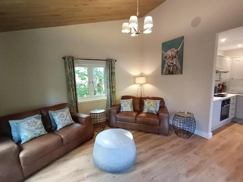 a living room with two couches and a table at Breckland Lodge 1 with Hot Tub in Belladrum