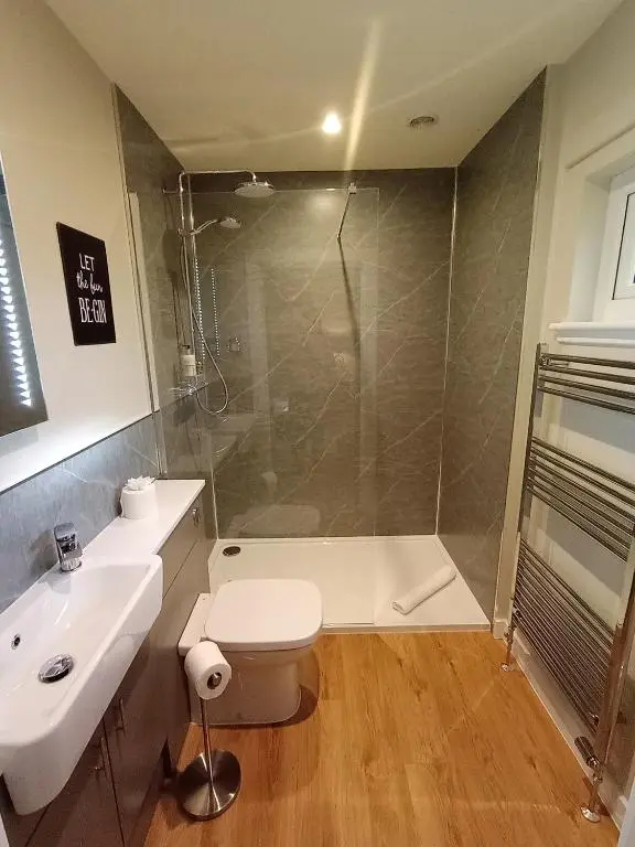 a bathroom with a shower and a toilet and a sink at Breckland Lodge 1 with Hot Tub in Belladrum