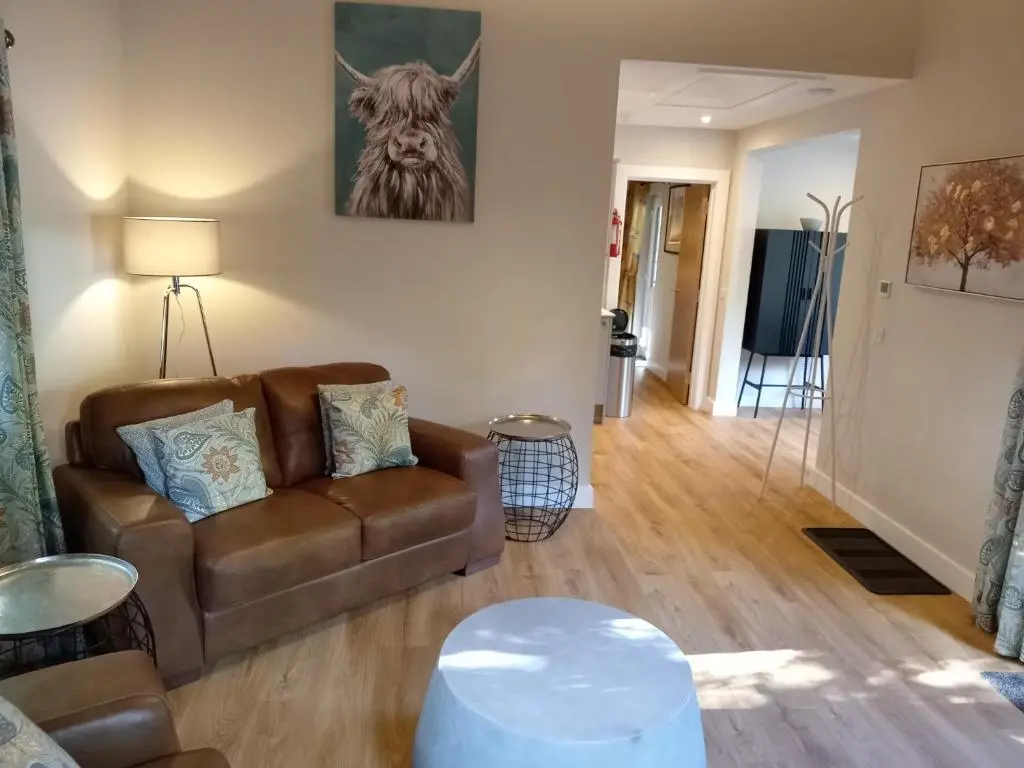 a living room with a couch and a table at Breckland Lodge 1 with Hot Tub in Belladrum