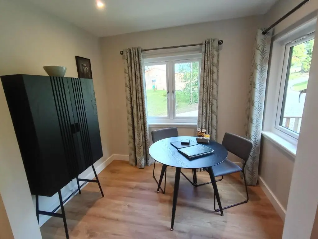 a dining room with a table and chairs and a window at Breckland Lodge 1 with Hot Tub in Belladrum