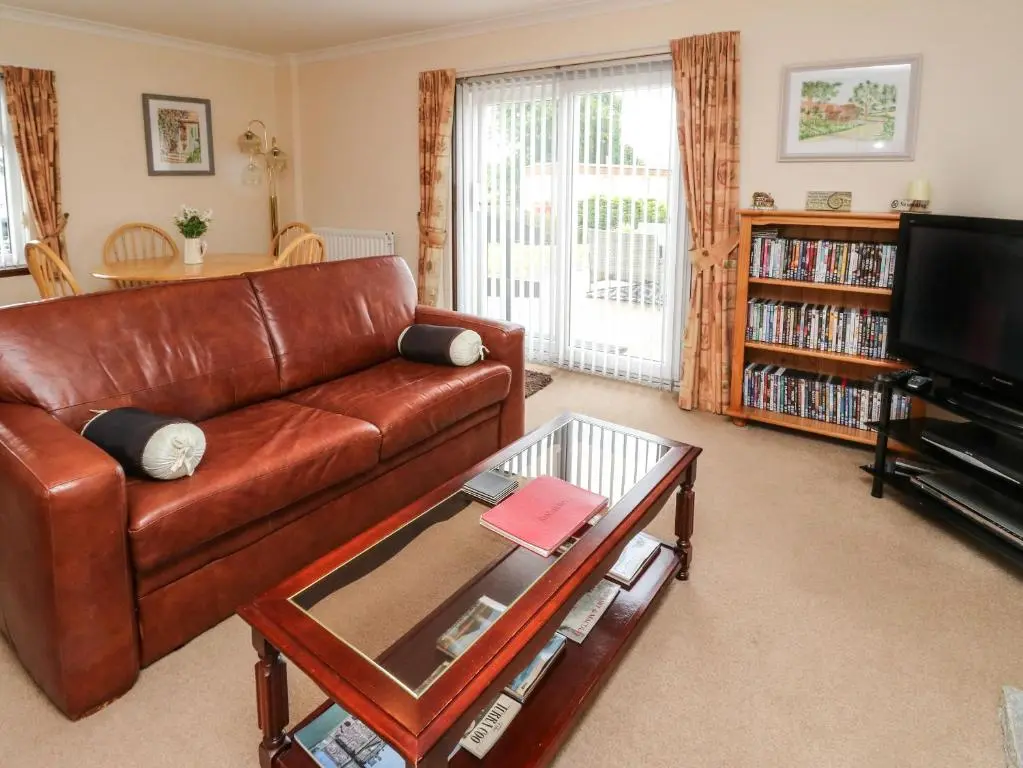 a living room with a brown leather couch and a tv at Bide-a-While in Marnoch