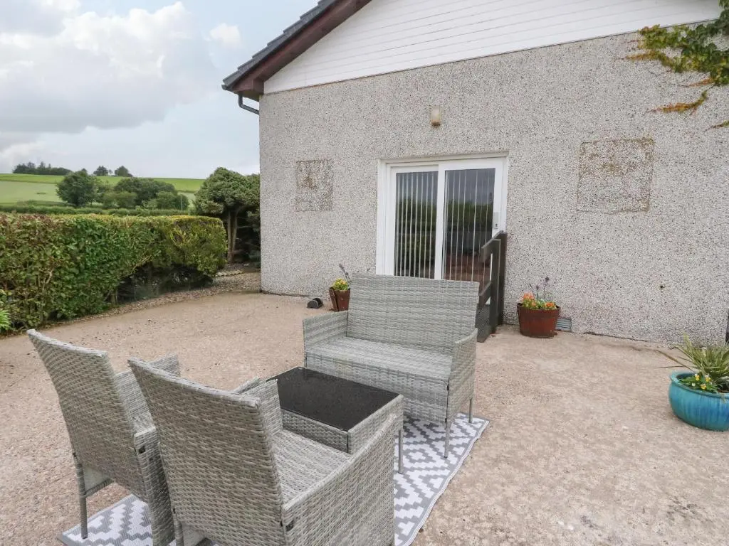 a patio with wicker chairs and a table at Bide-a-While in Marnoch