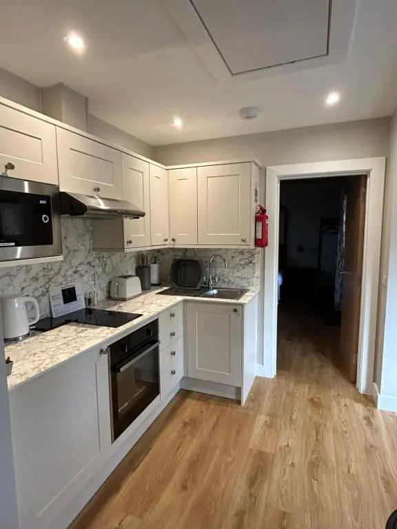 a kitchen with white cabinets and a wooden floor at Breckland Lodge 2 with Hot Tub in Belladrum