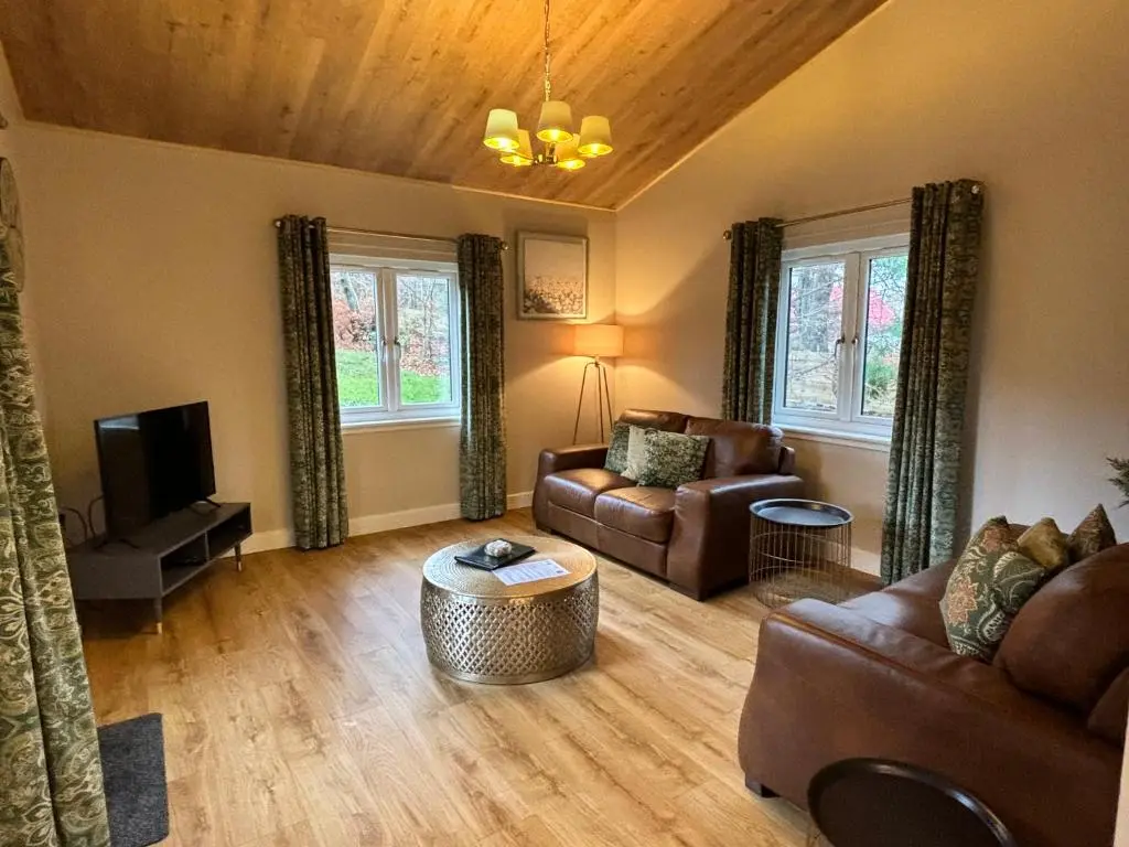 a living room with a couch and a tv at Breckland Lodge 2 with Hot Tub in Belladrum