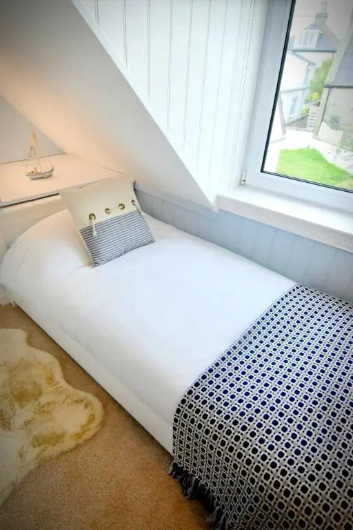 a small bed in a room with a window at Dram Cottage, Findhorn Bay in Forres