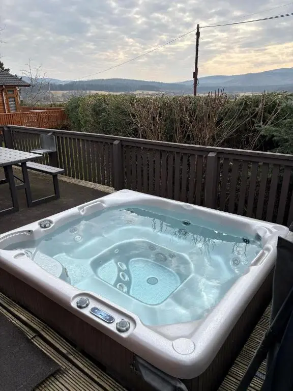 a jacuzzi tub sitting on top of a deck at Clochnaben lodge in Strachan