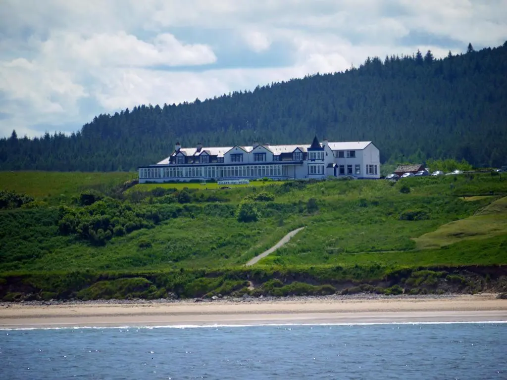 a large house on top of a hill next to the ocean at Cullen Bay Hotel in Cullen