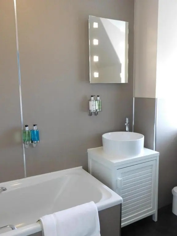 a bathroom with a sink and a tub and a mirror at Cullen Bay Hotel in Cullen
