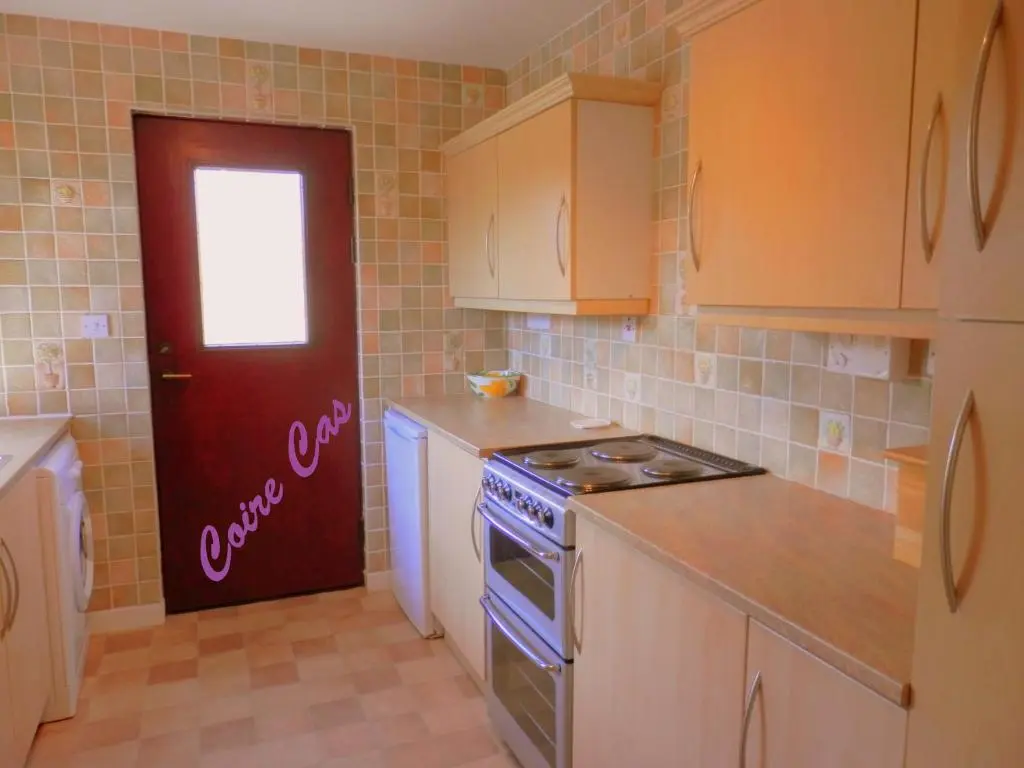 a kitchen with a stove and a red door at Cairngorm Highland Bungalows in Aviemore