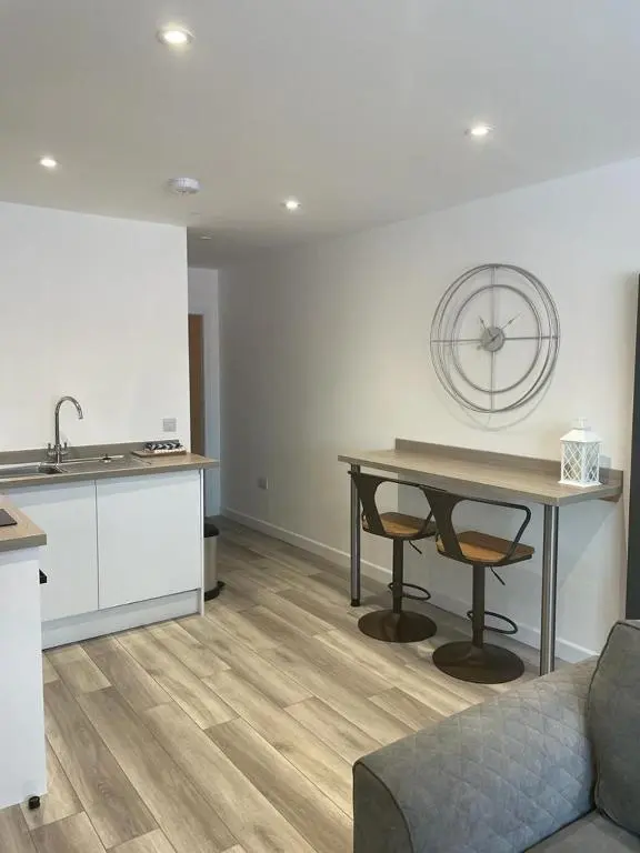 a living room with a table and a kitchen at Simpsons in Lairg