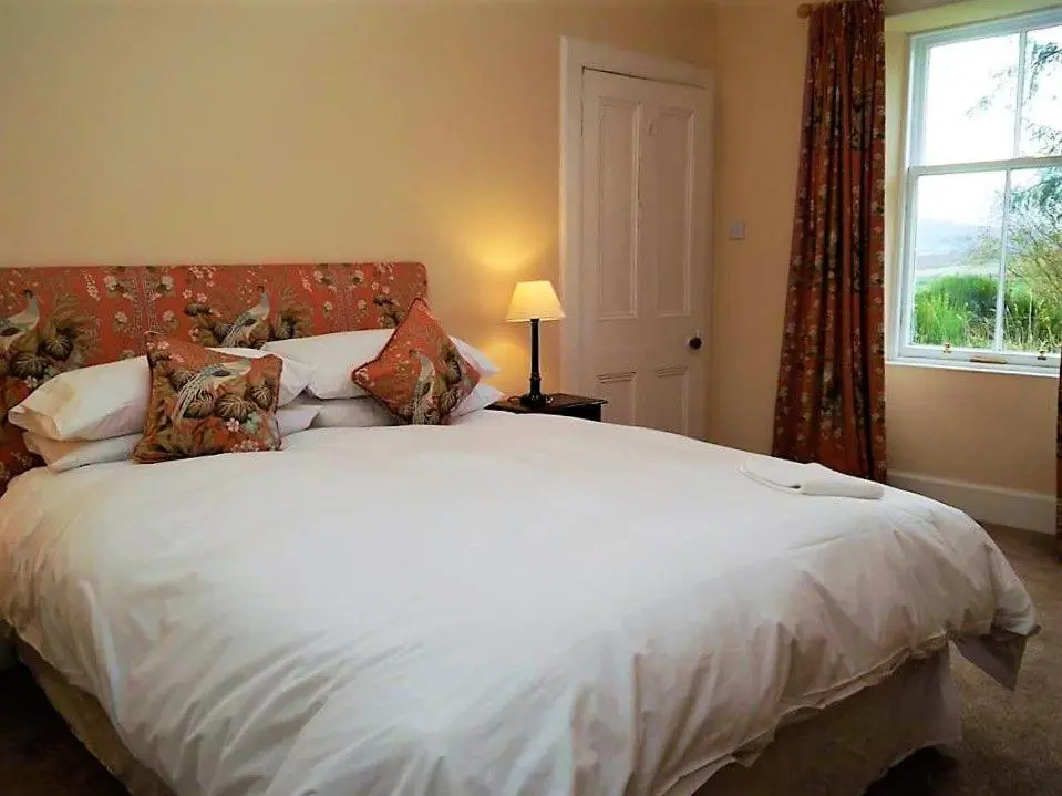 a bedroom with a large white bed with a window at Bogroy in Aberlour