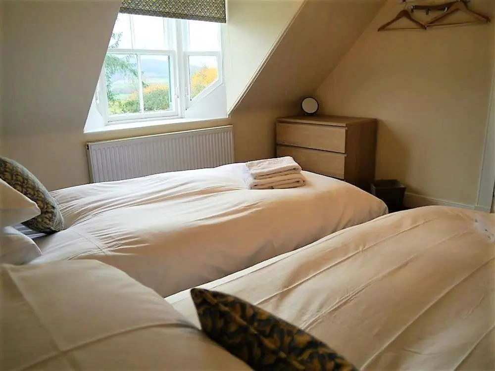 a attic bedroom with two beds and a window at Bogroy in Aberlour