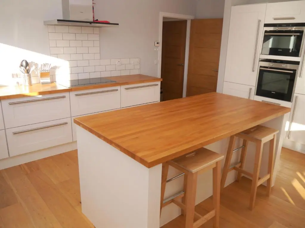 a kitchen with white cabinets and a wooden counter top at Laundry Cottage in Aberlour