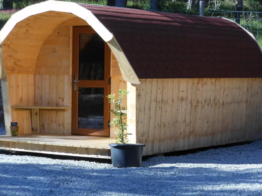 a small wooden building with a door and a potted plant at Camping Pod Heaven in Brackla